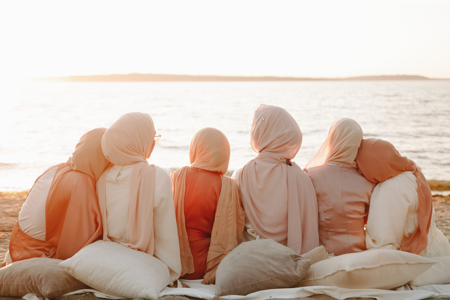 Back View of Six Women Wearing Hijabs while Sitting on the Beach